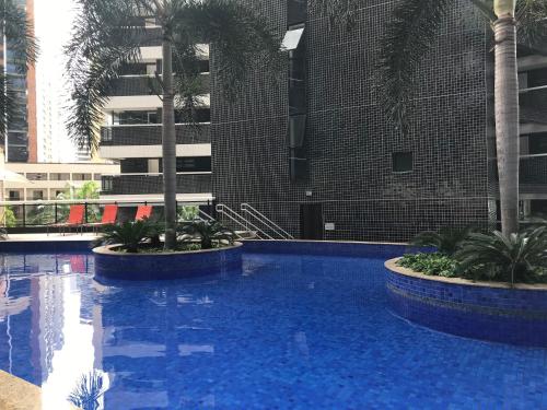 uma grande piscina com palmeiras e um edifício em Flat Beira-Mar Landscape em Fortaleza