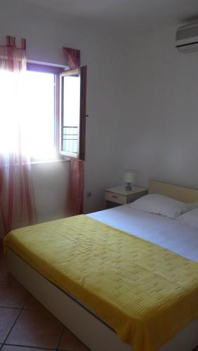 a bedroom with a bed with a yellow blanket on it at Guest house Živković in Sveti Stefan
