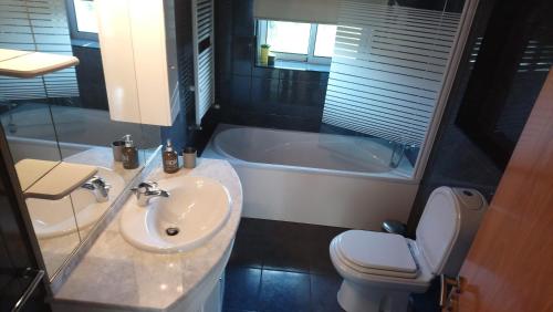 a bathroom with a sink and a toilet and a tub at Beach House - Between Porto and Viana do Castelo in Esposende