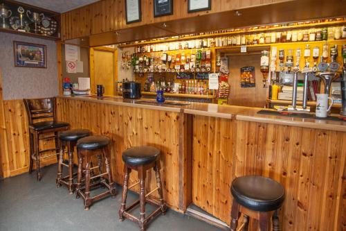 a bar with five stools at a wooden counter at Seaview John O Groats Hotel in John O Groats
