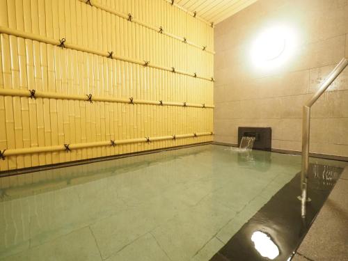 an empty swimming pool in a gym with yellow walls at Tabino Hotel Kurashiki Mizushima in Kurashiki