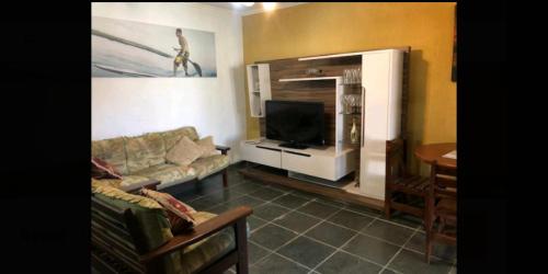 sala de estar con sofá y TV de pantalla plana en Casa na Praia c/Piscina e Churrasqueira, en Itanhaém