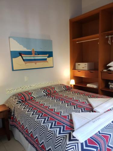 a bed with a colorful comforter in a bedroom at Pousada Pedra da Gaivota in Bombinhas
