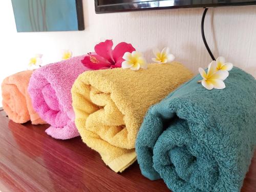 three towels on a table with flowers on them at Résidence Les Badamiers --- Exotica Villa in Centre de Flacq