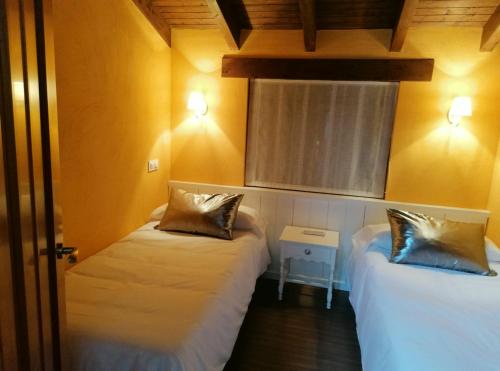 two beds in a room with yellow walls at El Cerrillo II in San Martín del Pimpollar