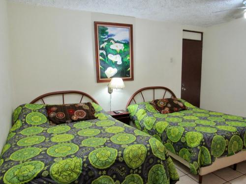 um quarto com duas camas e uma foto na parede em Hotel La Guaria Inn & Suites em Alajuela