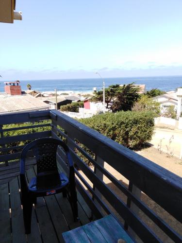 a chair sitting on a deck with a view of the ocean at Hostal F in El Quisco