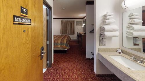 Waconia Inn and Suites في Waconia: غرفه فندقيه بحمام مع مغسله وسرير
