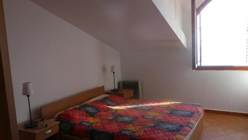 a bedroom with a bed with a colorful comforter and a window at Guest house Živković in Sveti Stefan