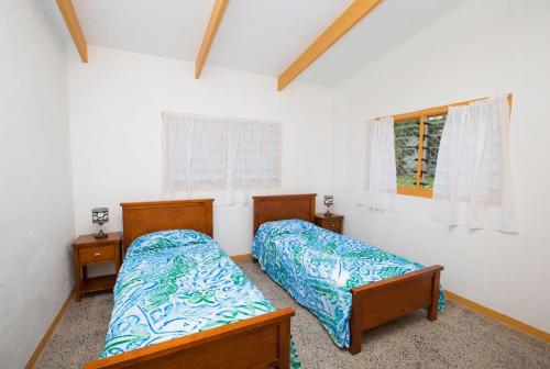 a bedroom with two beds and a window at Muri Homeland Villa in Rarotonga