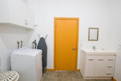 a bathroom with a yellow door and a sink at Muri Homeland Villa in Rarotonga