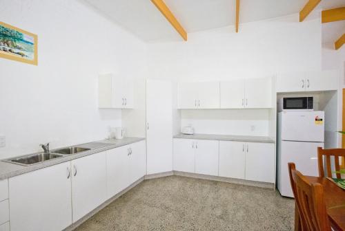 a white kitchen with a sink and a refrigerator at Muri Homeland Villa in Rarotonga