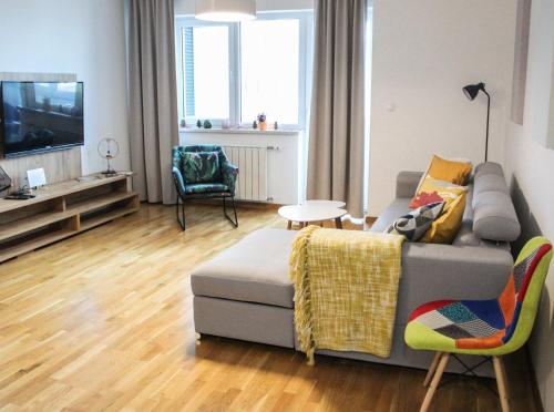a living room with a couch and a tv at Bright, modern & cozy apartment in Tuzla