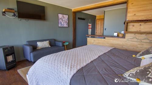a bedroom with a bed and a couch and a television at SaldeMar Playa Hermosa in Pichilemu