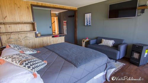 um quarto com uma cama, uma cadeira e uma televisão em SaldeMar Playa Hermosa em Pichilemu