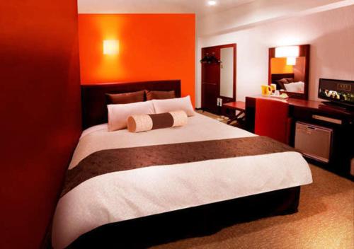 1 dormitorio con 1 cama grande y pared de color naranja en Kuretake-Inn Yaizuekimae, en Yaizu