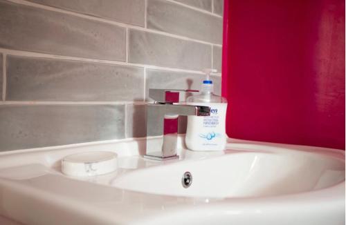 a bathroom sink with a bottle of soap on it at Tabs Cottage in Fowey