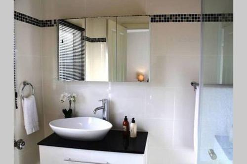 a bathroom with a sink and a mirror at Kenmaur Cottage in Kyneton