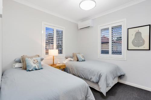 two beds in a white room with windows at Nell's Place in Toowoomba