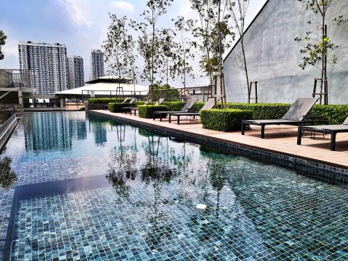 a swimming pool with benches next to a building at Tamarind Suites by BeeStay Management in Cyberjaya