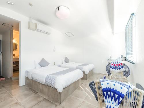 two beds in a white room with two chairs at Mykonos Resort Miura / Vacation STAY 62210 in Yokosuka