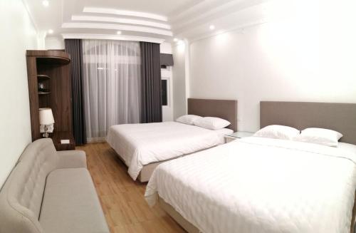a hotel room with two beds and a couch at Roma Hotel Noi Bai airport in Hanoi