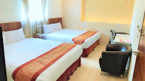 a hotel room with two beds and a chair at Taitung Z. Hotel in Taitung City