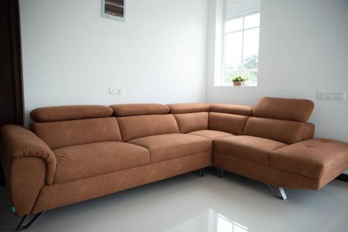 a brown couch in a living room with a window at White Castle in Wadduwa