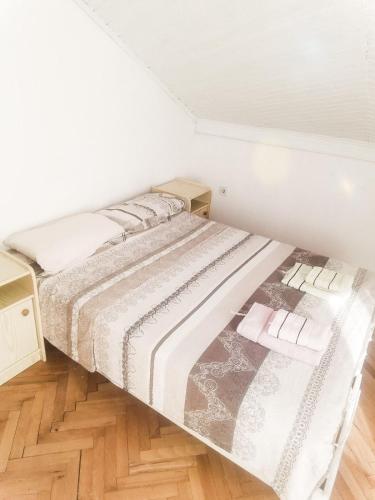 a bed in a white room with a wooden floor at Apartmani Braca2 in Kotor