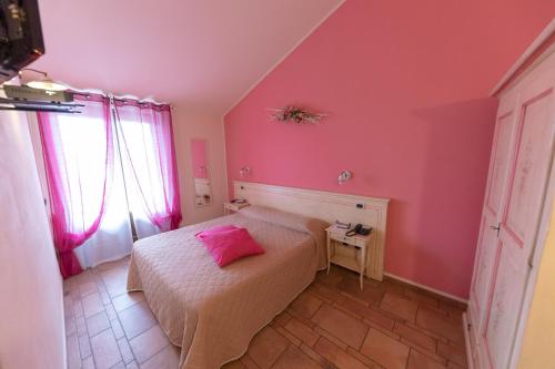 a bedroom with pink walls and a bed with a pink pillow at Agriturismo La Dimora Del Contadino in Mondovì