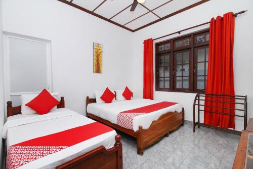 two beds in a room with red curtains at Leo's Home Stay in Colombo