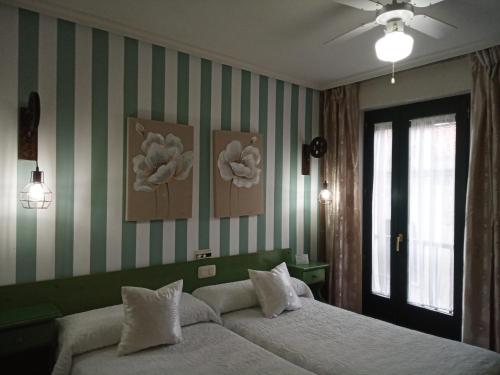 sypialnia z łóżkiem i zieloną i białą ścianą w paski w obiekcie Don Diego w mieście Avila