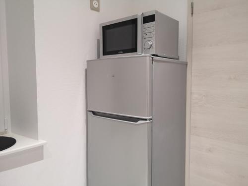 un micro-ondes au-dessus d'un réfrigérateur dans une cuisine dans l'établissement LE WILSON SUITE - Centre-ville - Gare - Tram, à Mulhouse