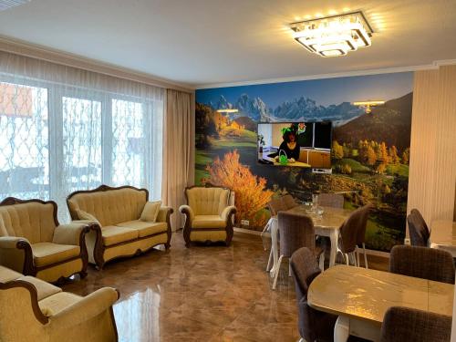 a living room with a tv and a painting on the wall at Hotel Diamond Kazbegi in Stepantsminda