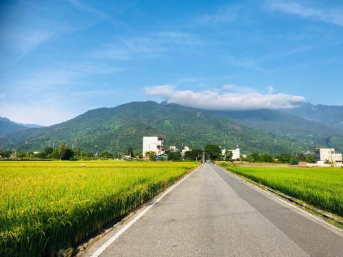 una strada attraverso un campo con le montagne sullo sfondo di PS Minshuku a Ji'an