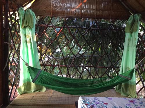 a hammock in a yurt with green curtains at mekong floating market Nam Giang homestay in Cai Be