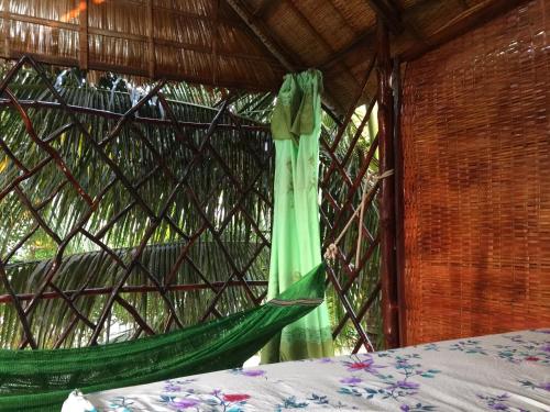 a hammock hanging in a room with a window at mekong floating market Nam Giang homestay in Cai Be