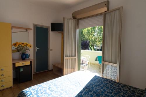 1 dormitorio con 1 cama y puerta corredera de cristal en Hotel Etna, en Riccione