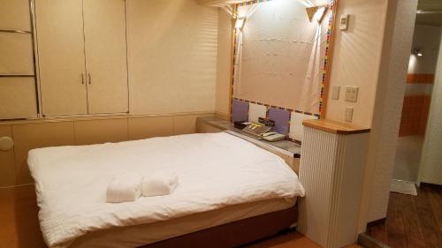 a small room with a bed with two towels on it at Hotel GOLF Yokohama (Adult Only) in Yokohama