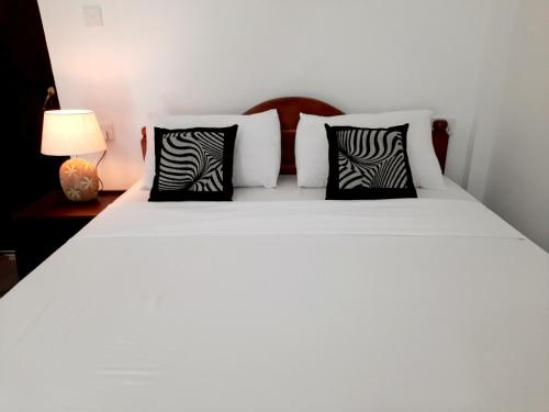 - une chambre avec un lit et des oreillers noirs et blancs dans l'établissement Dream Villa Sigiriya, à Sigirîya