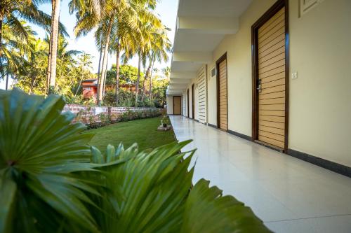 a corridor of a house with palm trees and plants at Golden Sands Resort, Morjim in Morjim