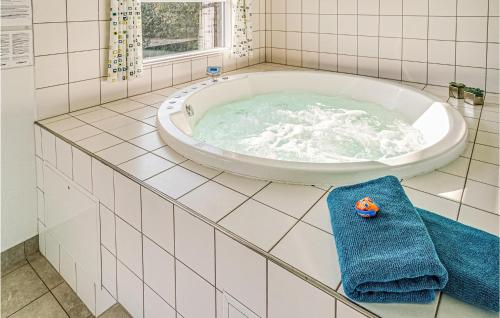 La salle de bains est pourvue d'une grande baignoire et d'une serviette bleue. dans l'établissement Gorgeous Home In Sydals With Indoor Swimming Pool, à Høruphav