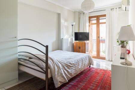 ein weißes Schlafzimmer mit einem Bett und einem Fenster in der Unterkunft Irodotou Studio in Thessaloniki