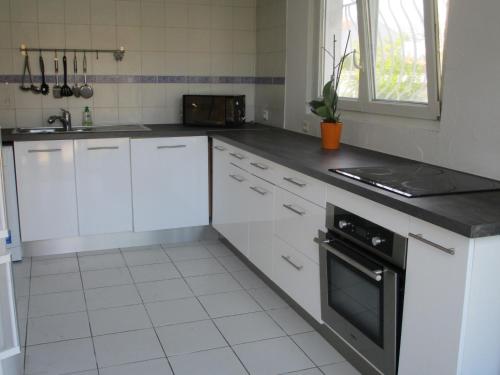 a kitchen with white cabinets and a black oven at REZ DE VILLA SIX-FOURS in Six-Fours-les-Plages