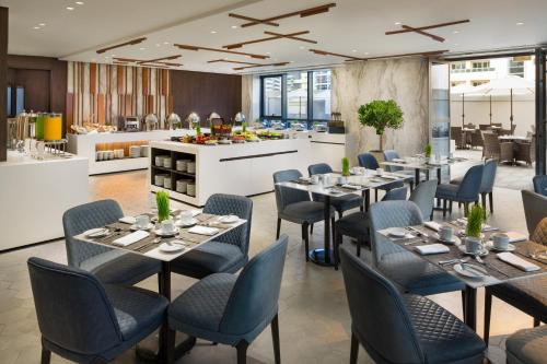 a restaurant with tables and chairs and a counter at Millennium Place Barsha Heights Hotel Apartments in Dubai