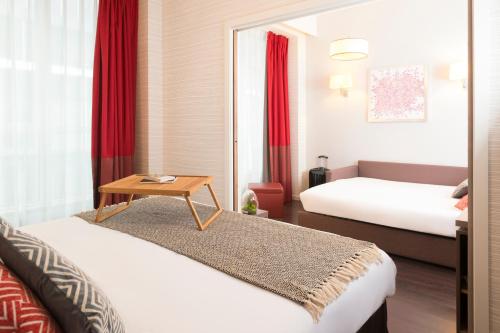 um quarto de hotel com duas camas e uma mesa em Aparthotel Adagio Brussels Grand Place em Bruxelas