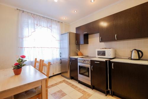 a kitchen with black cabinets and a table and a microwave at ОК! Красноармейская, 151 in Tomsk