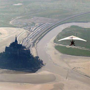 a person in an umbrella flying over a castle at Entre Mont St Michel et Merveille in Vains