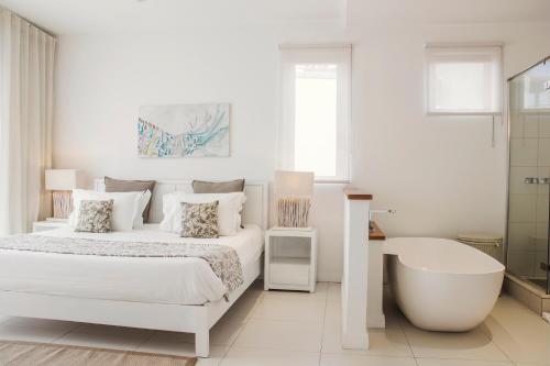 a white bedroom with a bed and a bath tub at 2 bedrooms charming apartment, West Island Resort in Rivière Noire