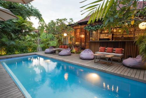 a swimming pool with purple pillows next to a house at Pangkung Sari Bed and Breakfast in Canggu